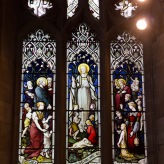 The people, both on earth and in heaven, gather around Jesus. Stained glass window Edgbaston Old Church.